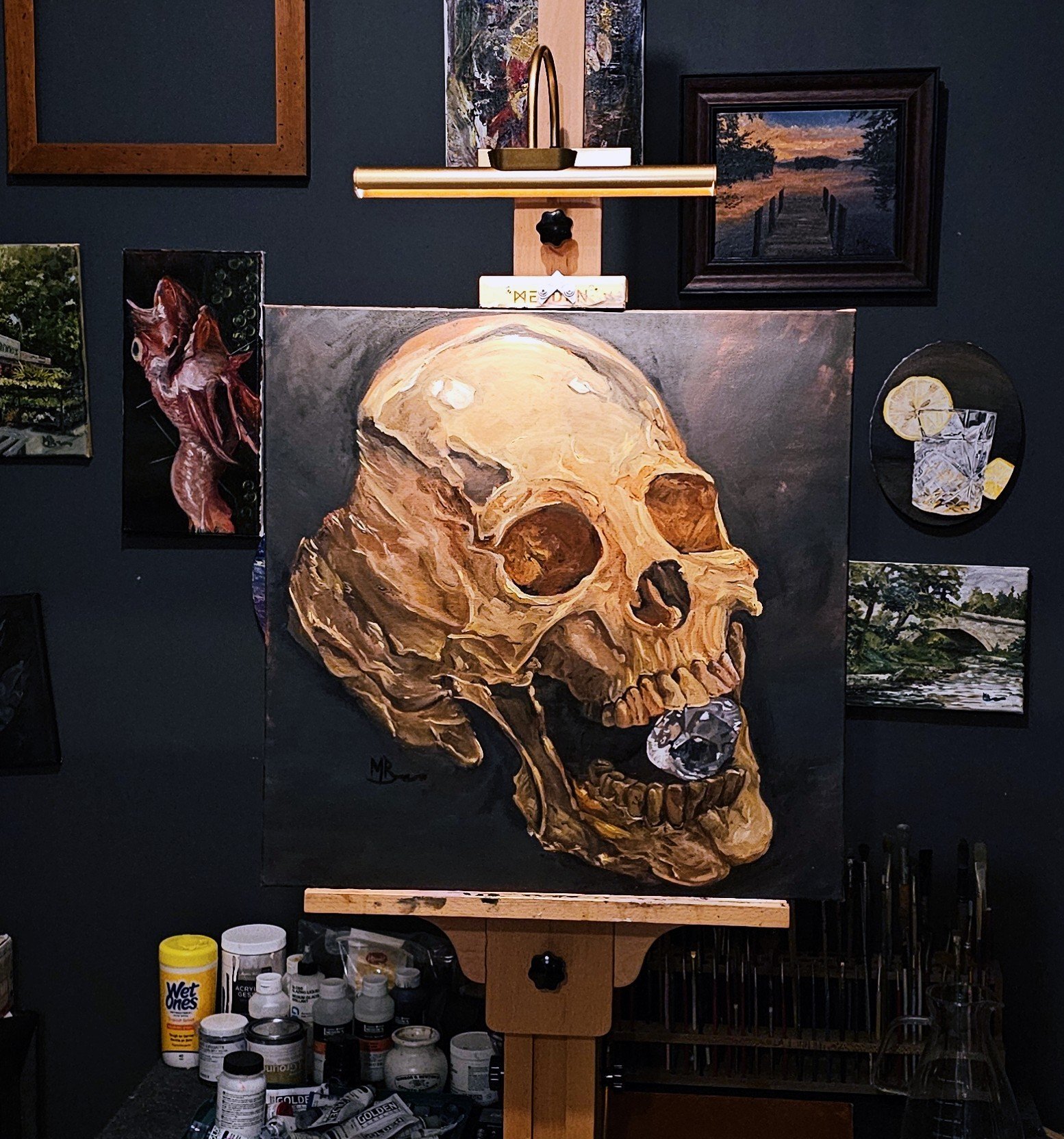 AMOR FATI
24x24 Oil on canvas
🖼️ Artwork Details
Artist: Matthew Bishop
Medium: Oil on Canvas
Theme: Memento Mori / Vanitas
Detailed Description
The piece features a dramatically lit , highly textured gold human skull rendered in warm, earthy tones of ochre, sienna, and bone white. The skull is positioned against a somber, dark background, which highlights the decay and rugged surface of the bone through strong chiaroscuro lighting.
The striking focal point is a large, brilliant-cut diamond wedged between the teeth. This element brilliantly contrasts the fragility and inevitable decay of the flesh (represented by the skull) with the cold, enduring beauty and material value of the jewel. The painting thus explores the classic Vanitas theme, reminding the viewer of the transient nature of wealth and earthly possessions in the face of mortality.
The artist's expressive, visible brushwork gives the skull an aged, almost sculptural quality, while the diamond is rendered with precise, reflective detail. - Image 2